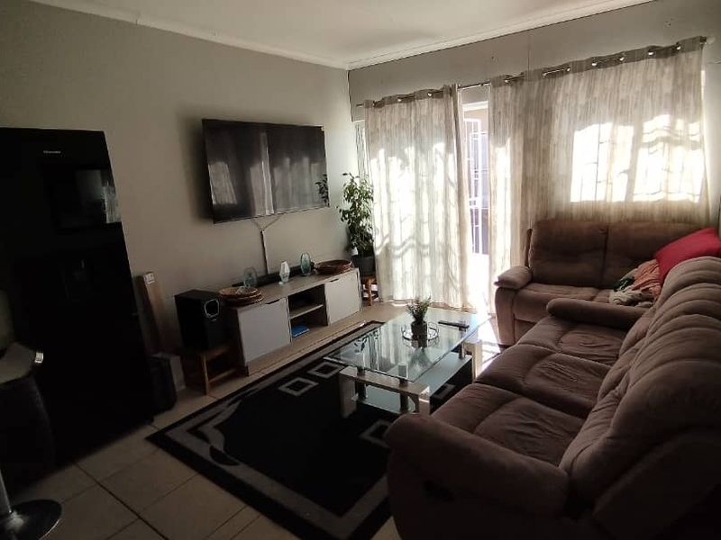 A living room featuring tiled flooring and a sliding glass door providing access to the exterior, offering a functional and comfortable living space.