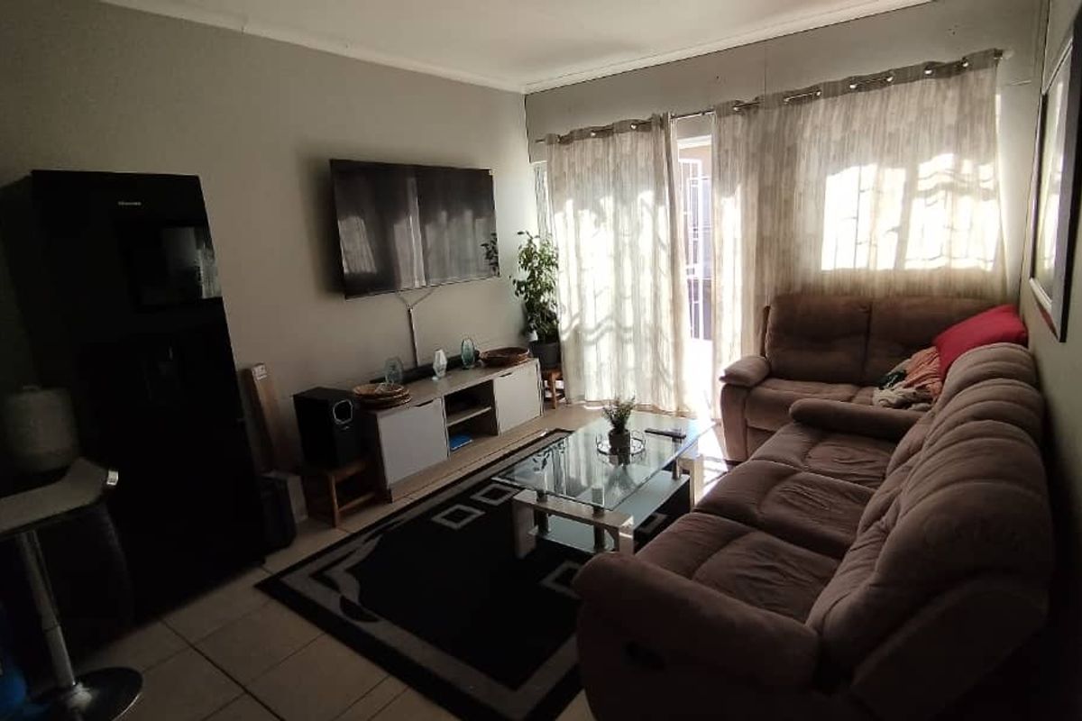 A living room featuring tiled flooring and a sliding glass door providing access to the exterior, offering a functional and comfortable living space.