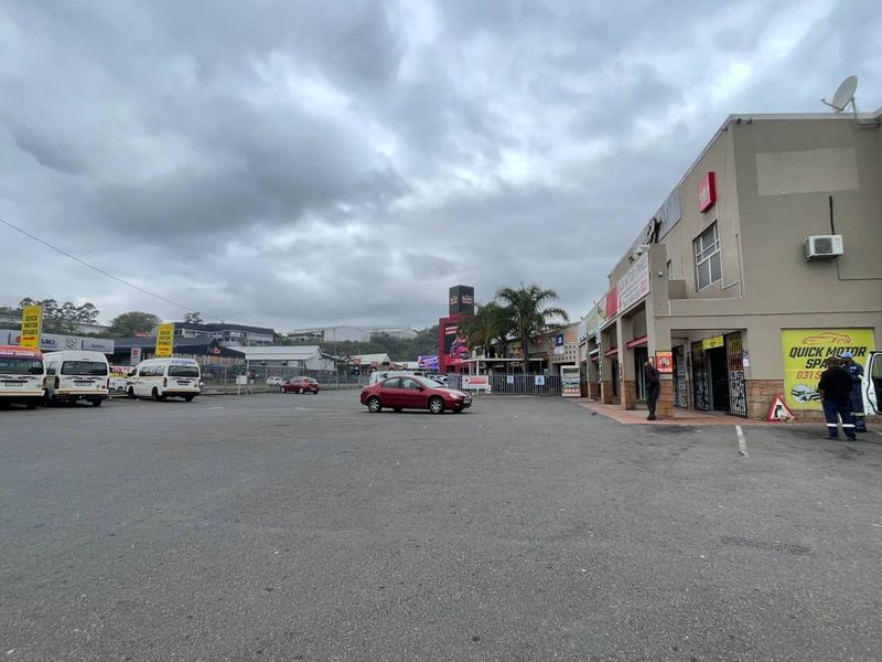 Exterior view of an industrial commercial property featuring a large asphalt parking area and building frontage with signage.