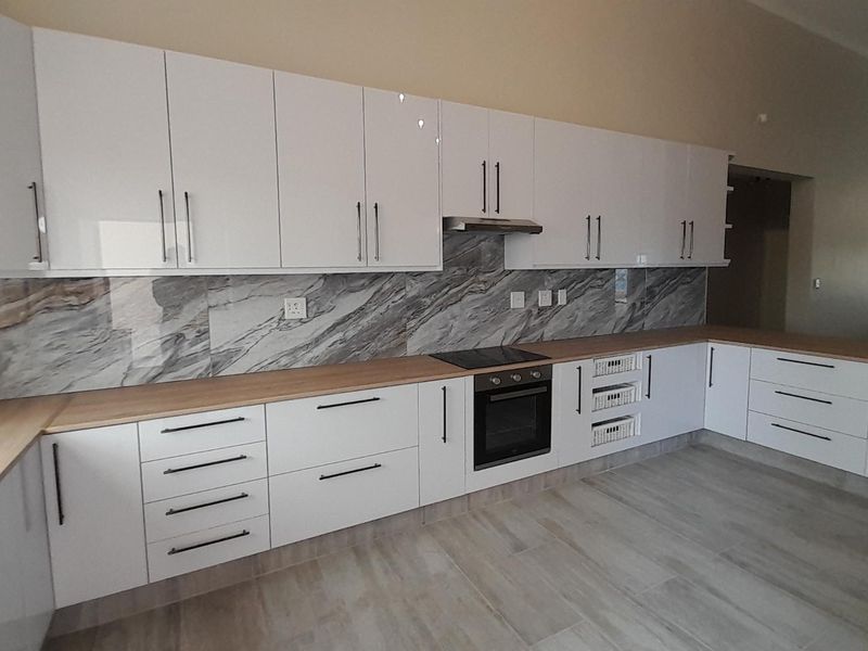 Modern kitchen featuring white high-gloss cabinetry, marble-look splashback, wooden countertops, and integrated appliances including an oven and hob.