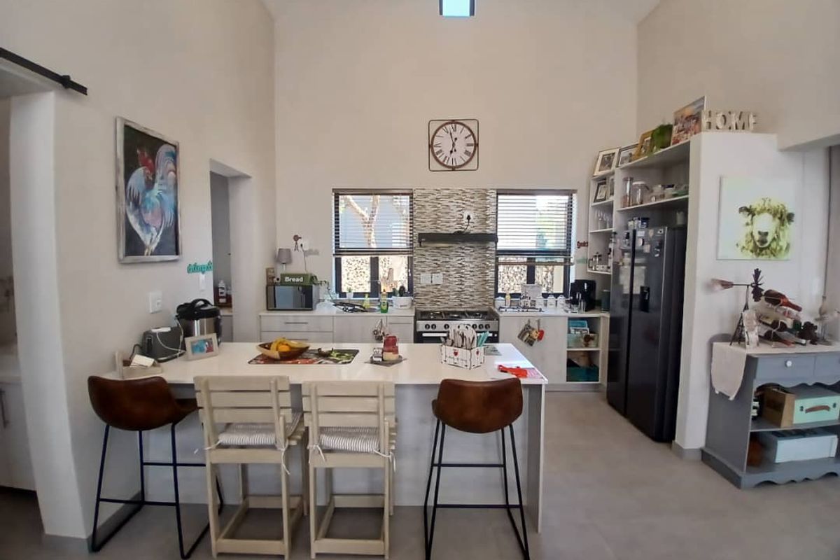 Spacious kitchen featuring a central island, built-in oven and hob, tiled splashback, and a high vaulted ceiling with a skylight for natural light.