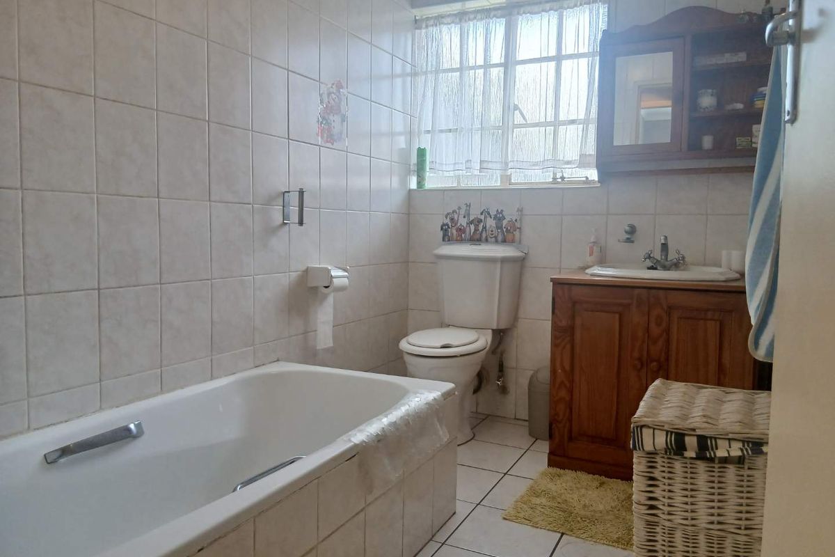 A functional bathroom featuring tiled walls and flooring, a built-in vanity with basin, a standard toilet, and a bathtub.