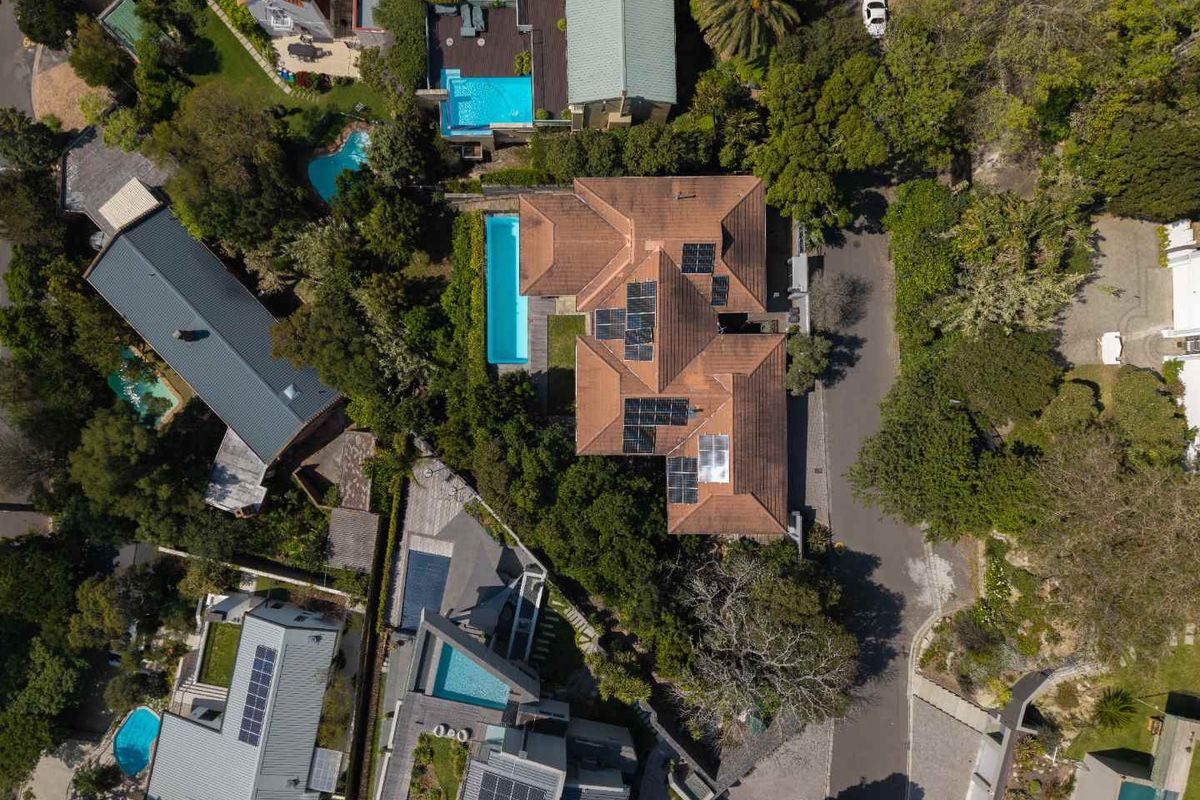 Aerial view of the property showcasing the roof structure, solar panel installation, and private swimming pool set within a landscaped garden.