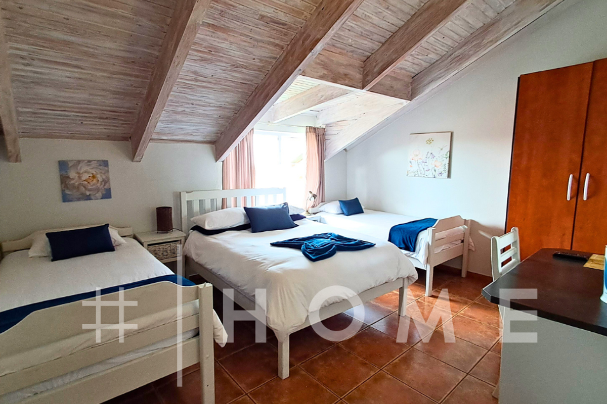 Spacious bedroom featuring a vaulted timber-beamed ceiling, terracotta floor tiles, and built-in cabinetry.