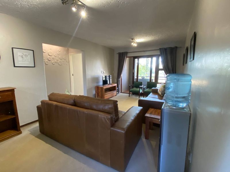 A comfortable living room featuring carpeted flooring, recessed ceiling lighting, and a sliding glass door providing access to an outdoor area.