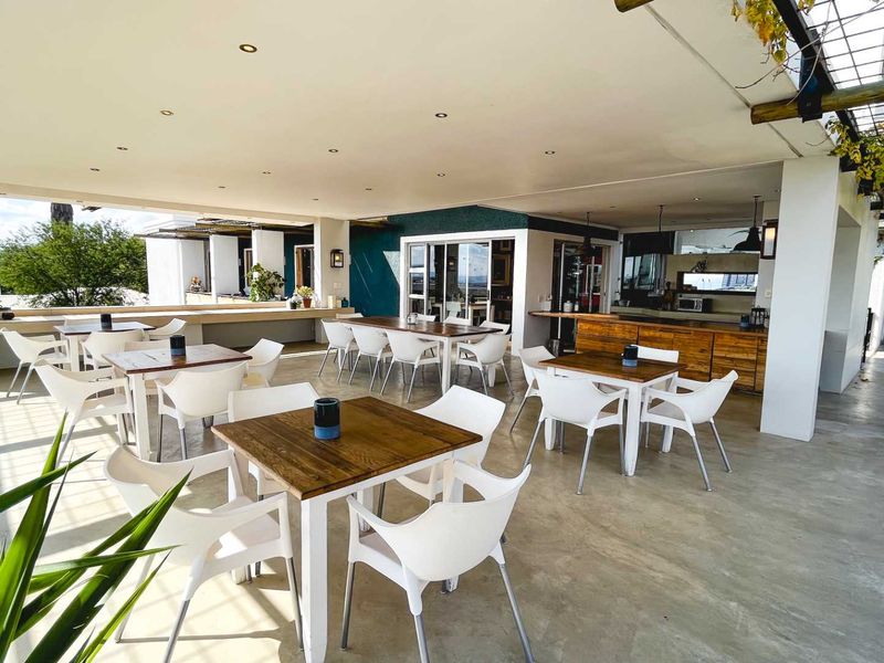 A spacious covered outdoor patio area featuring a built-in bar counter, concrete flooring, and recessed lighting, ideal for guest house dining or entertainment.
