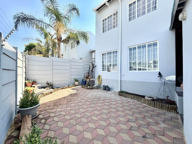 A private rear courtyard featuring paved flooring and a secure precast concrete boundary wall, providing a low-maintenance outdoor space for the townhouse.