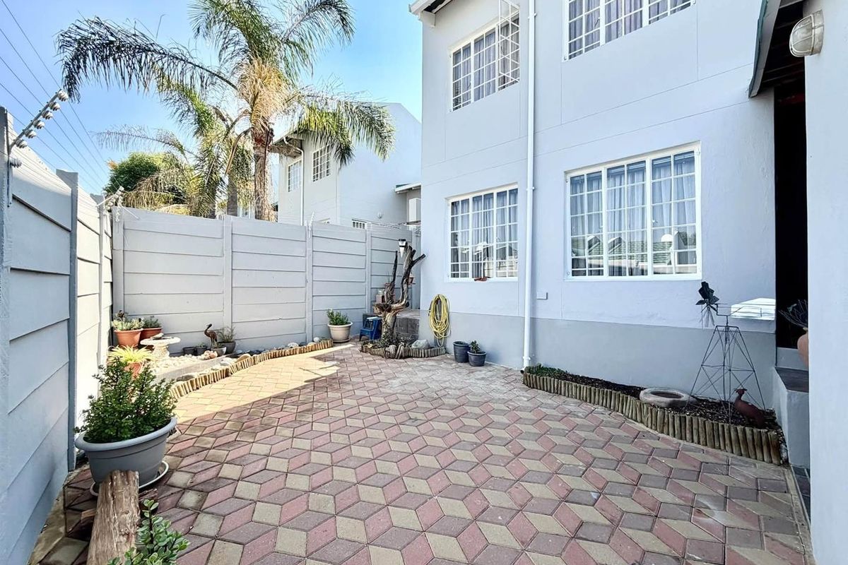 A private rear courtyard featuring paved flooring and a secure precast concrete boundary wall, providing a low-maintenance outdoor space for the townhouse.