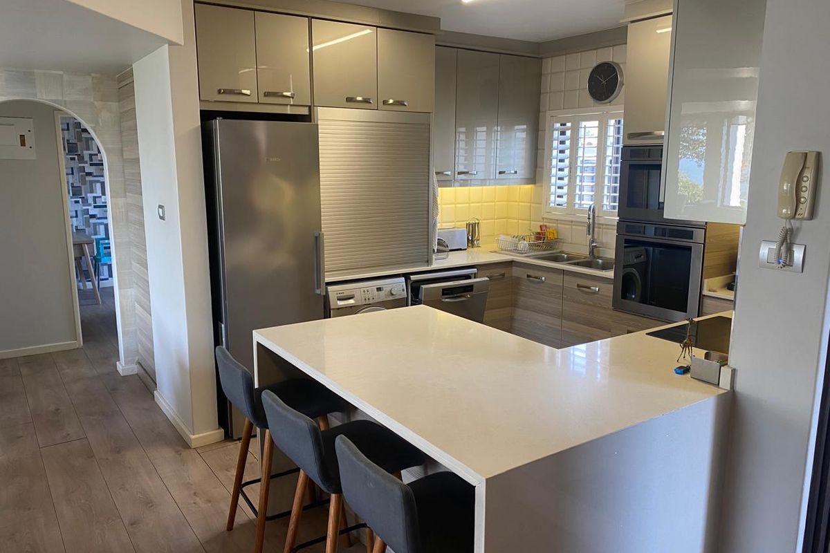 Modern kitchen featuring sleek cabinetry, stone countertops, a breakfast bar, and integrated appliances, including a built-in oven and microwave.