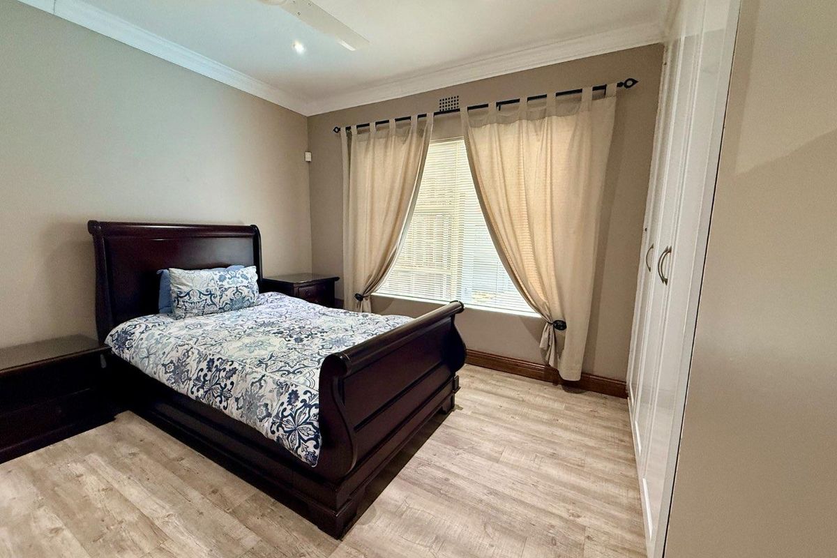 A well-maintained bedroom featuring light wood-look flooring, built-in white cabinetry, and a ceiling fan.