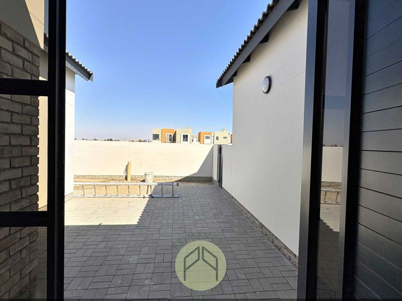 A private paved rear courtyard area enclosed by boundary walls, viewed from an interior doorway.