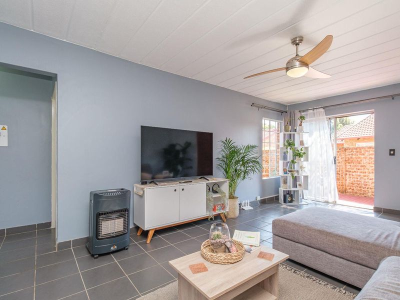 A living room featuring tiled flooring, a ceiling fan, and a sliding glass door providing access to the exterior.