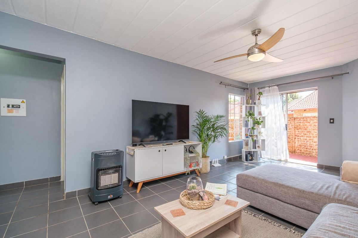 A living room featuring tiled flooring, a ceiling fan, and a sliding glass door providing access to the exterior.