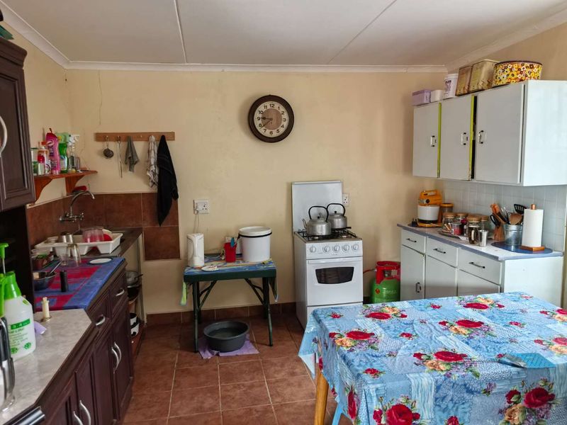 A functional kitchen featuring tiled flooring, built-in cabinetry, and a gas stove, offering a practical layout with potential for cosmetic updates.