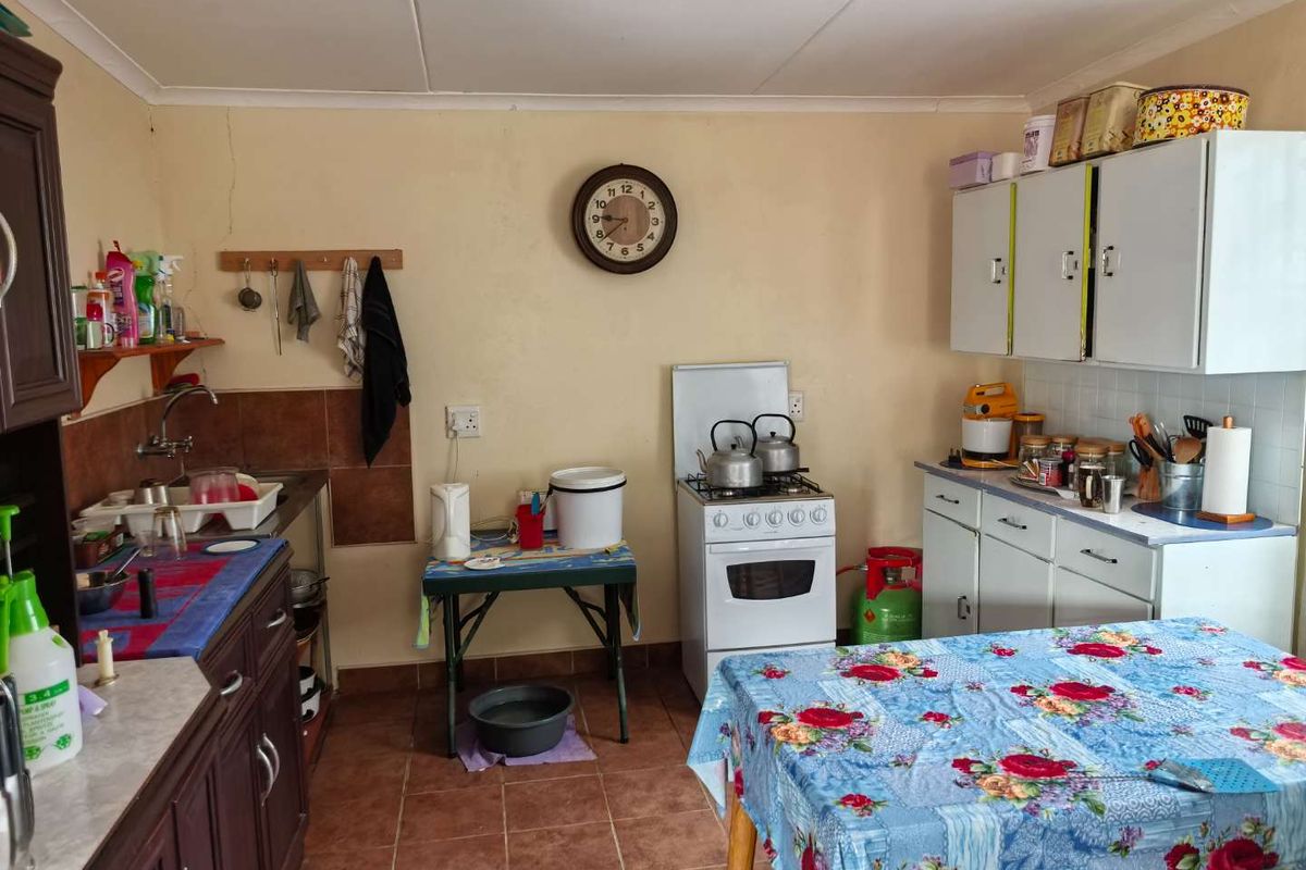 A functional kitchen featuring tiled flooring, built-in cabinetry, and a gas stove, offering a practical layout with potential for cosmetic updates.