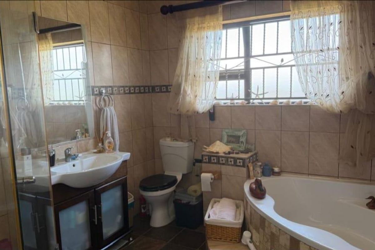 A functional bathroom featuring a corner bathtub, a vanity with a basin, a toilet, and full-height wall tiling.