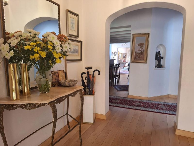 Welcoming entrance hall featuring hardwood flooring, an elegant arched doorway leading to the living area, and a decorative wall niche.