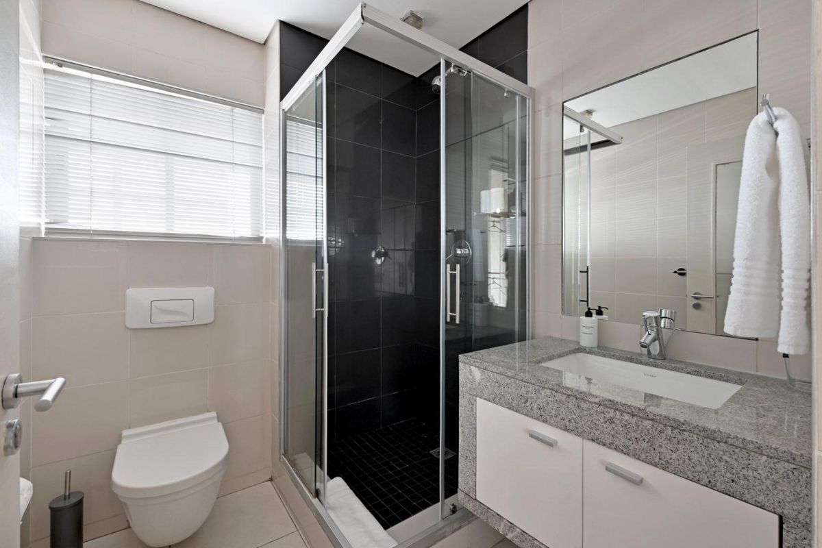 Modern bathroom featuring a glass-enclosed shower, granite vanity countertop with under-mount sink, and wall-mounted toilet.