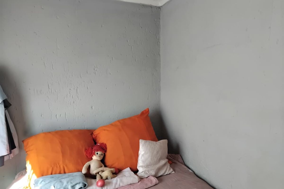 A corner view of a bedroom featuring textured grey walls and coving.