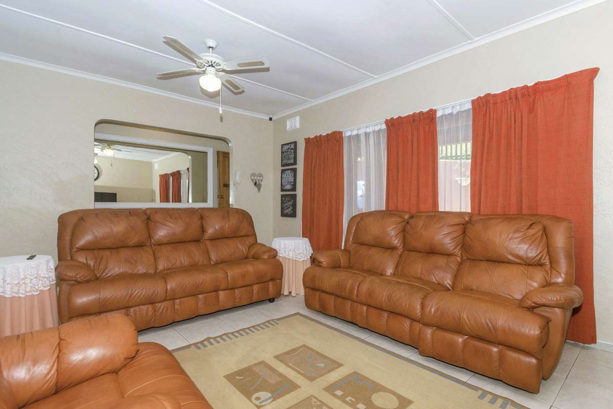 A comfortable living room featuring tiled flooring, a ceiling fan, and a large arched wall opening connecting to an adjacent space.