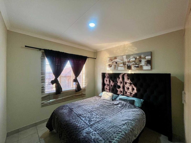 A standard bedroom featuring tiled flooring, neutral wall finishes, and a built-in cupboard, providing a functional and comfortable sleeping space.