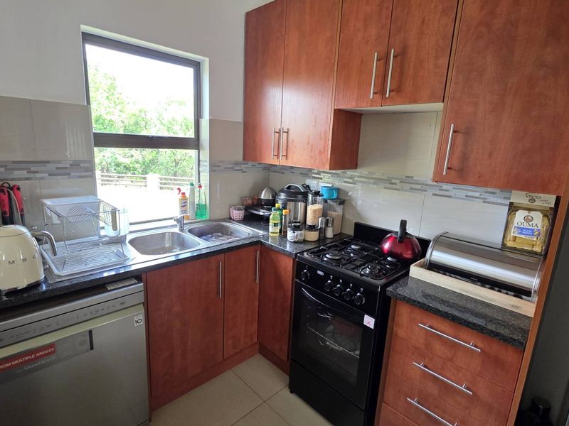A functional kitchen featuring wood-finish cabinetry, granite countertops, a double basin sink, and a built-in gas stove with oven.
