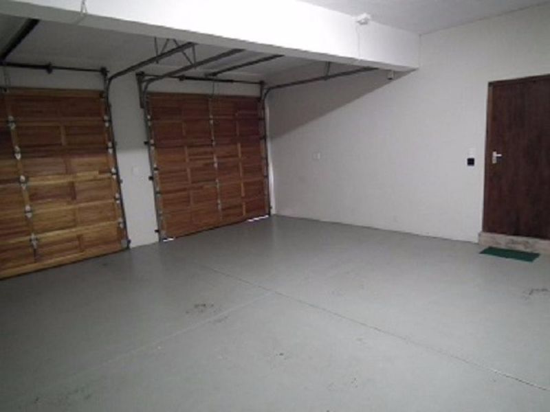 Spacious double garage featuring wooden sectional doors, painted concrete flooring, and convenient internal access to the main dwelling.