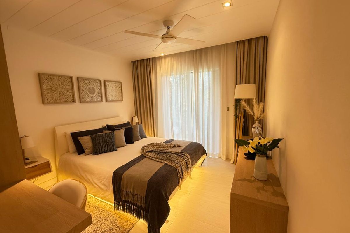 A well-appointed bedroom featuring recessed ceiling lighting, a modern ceiling fan, and large sliding glass doors with floor-to-ceiling curtains.