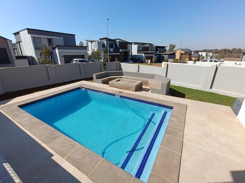 Modern outdoor entertainment area featuring a swimming pool, tiled patio, and a built-in concrete bench with a central fire pit.