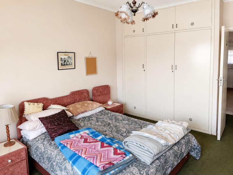 A bedroom featuring built-in cupboards and a ceiling light fixture, offering a functional space with potential for modern updates.