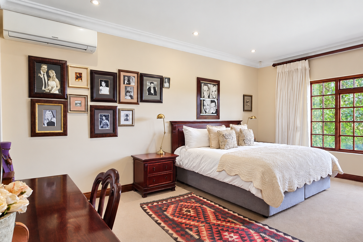 A well-maintained bedroom featuring timber-framed windows, neutral wall tones, and a wall-mounted split-system air conditioner.