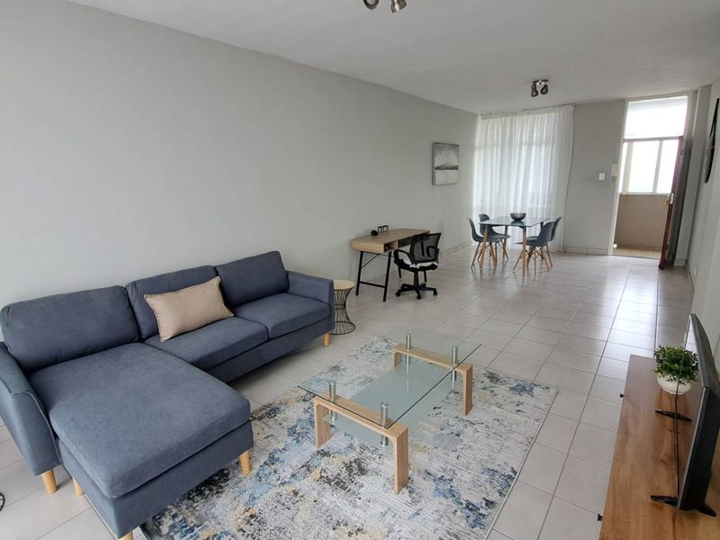 Spacious open-plan living and dining area featuring neutral wall finishes, tiled flooring, and direct access to an outdoor balcony space.