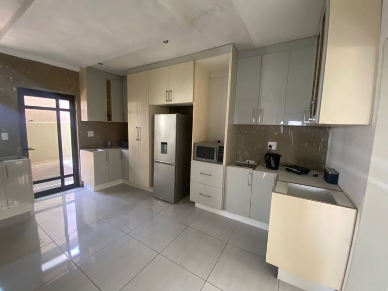 Kitchen featuring built-in cabinetry and tiled flooring, currently requiring completion of wall finishes and backsplash installation.
