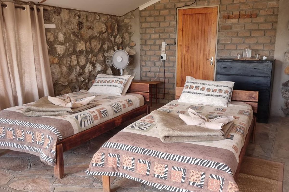 Rustic bedroom featuring exposed stone and brick walls, vaulted ceiling, and natural stone flooring, creating a unique farm-style atmosphere.