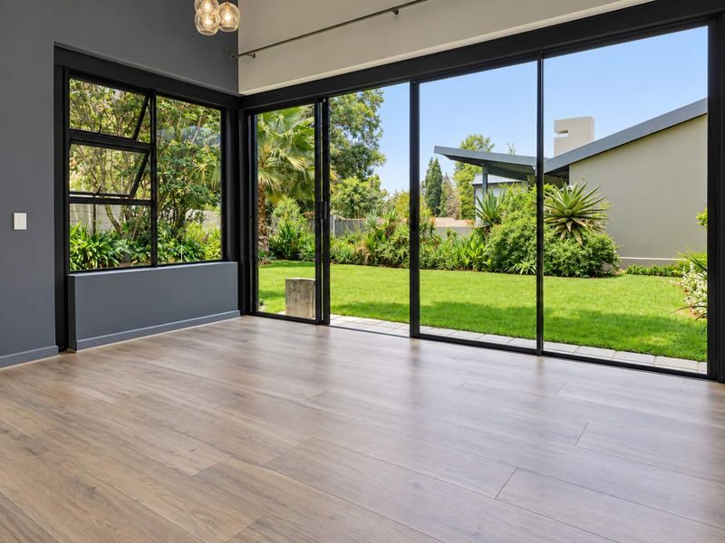 Bright and modern living area featuring high-quality laminate flooring and expansive sliding glass doors that provide seamless access to the lush garden.