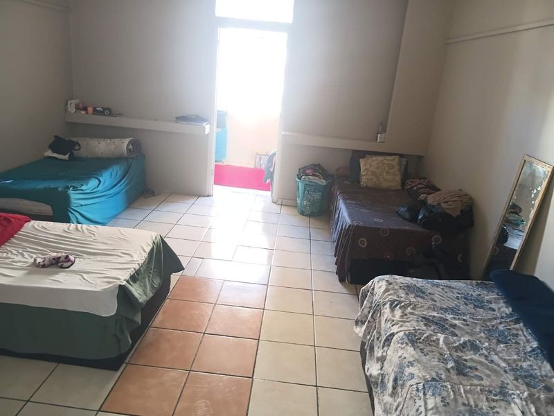 A bedroom featuring tiled flooring and built-in shelving, with direct access to an outdoor balcony area.
