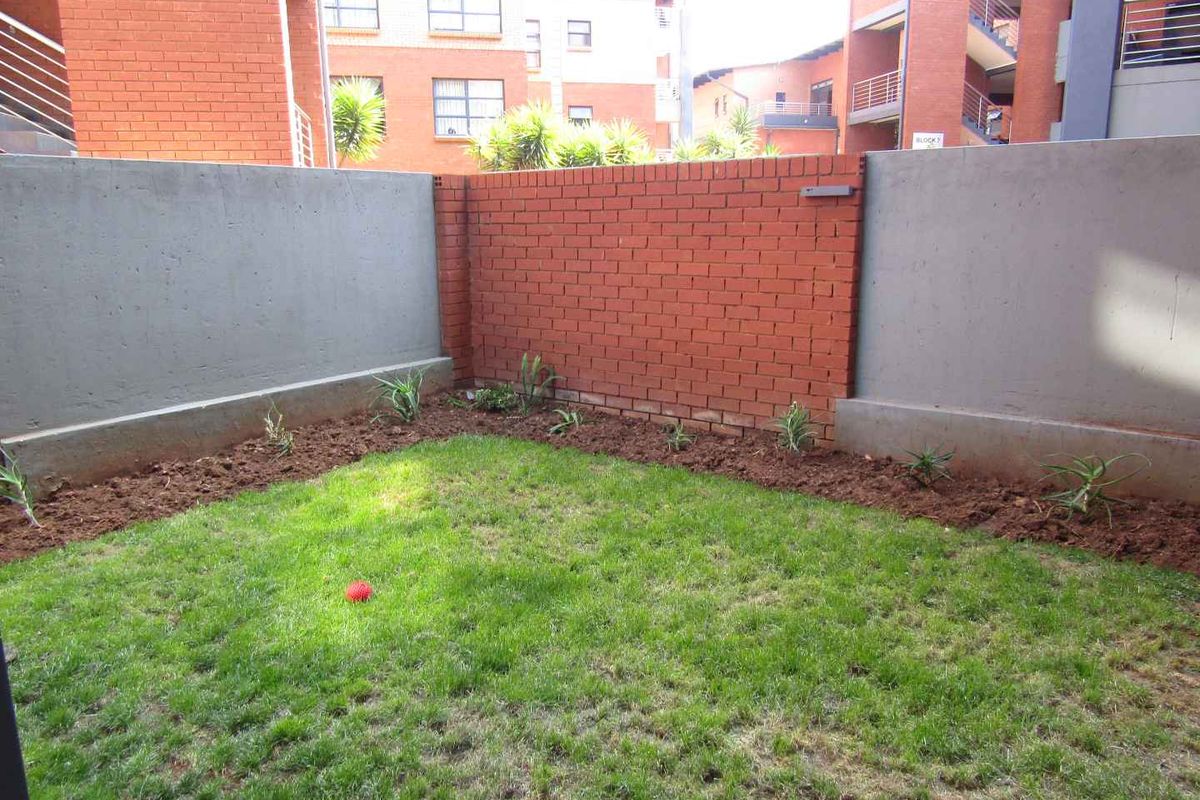 A private rear garden area featuring a combination of brick and concrete boundary walls and a small lawn.