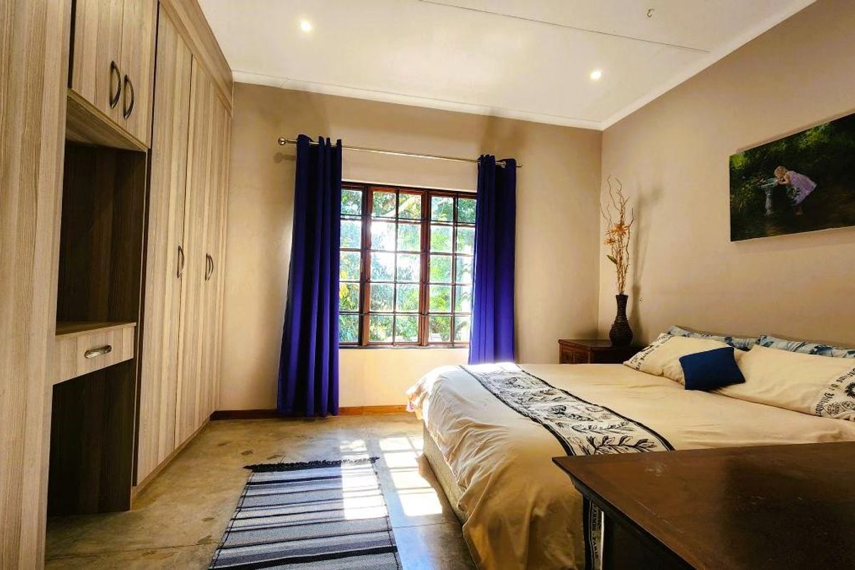 A well-lit bedroom featuring polished concrete floors, ample built-in cupboard space, and large windows allowing for natural light.