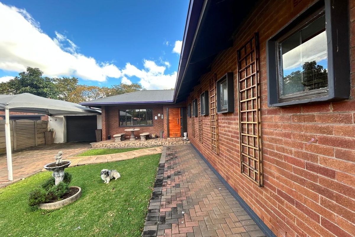 A view of the rear exterior of the house, featuring a brick facade, paved walkway, and a small garden area.