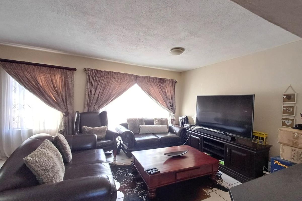 A comfortable living room featuring tiled flooring and large windows, providing a functional space for relaxation and entertainment.