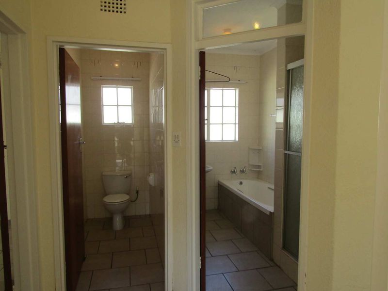 A view from the hallway looking into a separate toilet and a bathroom featuring a bathtub and shower enclosure.