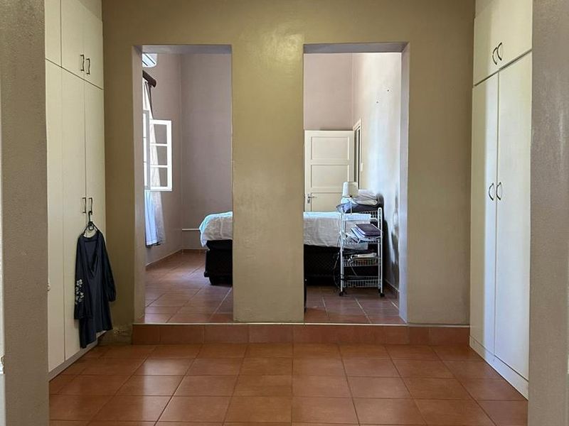 A bedroom featuring built-in cupboards, tiled flooring, and a coved ceiling, with an open transition to an adjacent sleeping area.