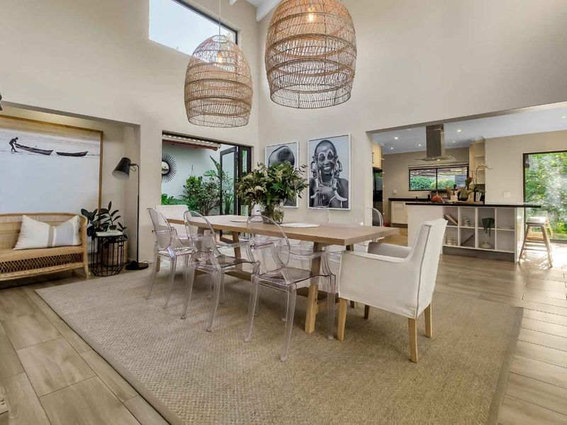 Spacious open-plan dining and kitchen area featuring double volume ceilings, clerestory windows, and seamless flow to the outdoor patio through bi-fold doors.