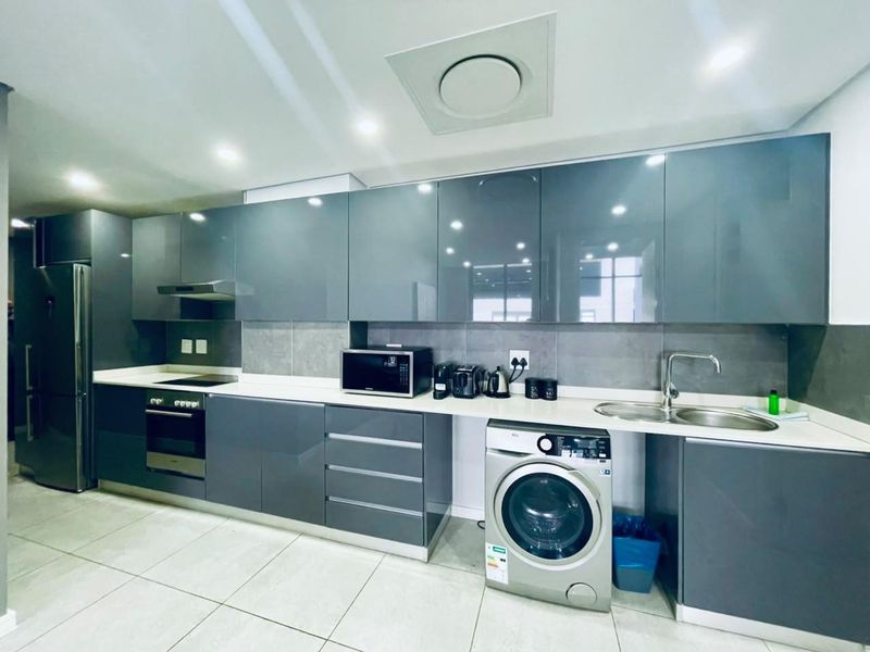Modern kitchen featuring sleek grey cabinetry, stone countertops, integrated appliances, and high-quality finishes throughout.