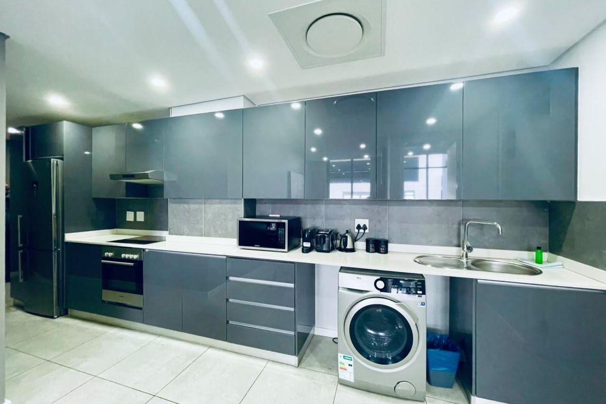 Modern kitchen featuring sleek grey cabinetry, stone countertops, integrated appliances, and high-quality finishes throughout.