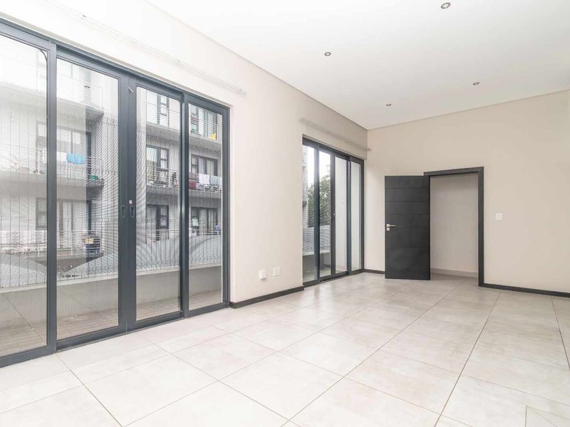 A bright, empty living area featuring large sliding glass doors that provide ample natural light and access to the exterior.
