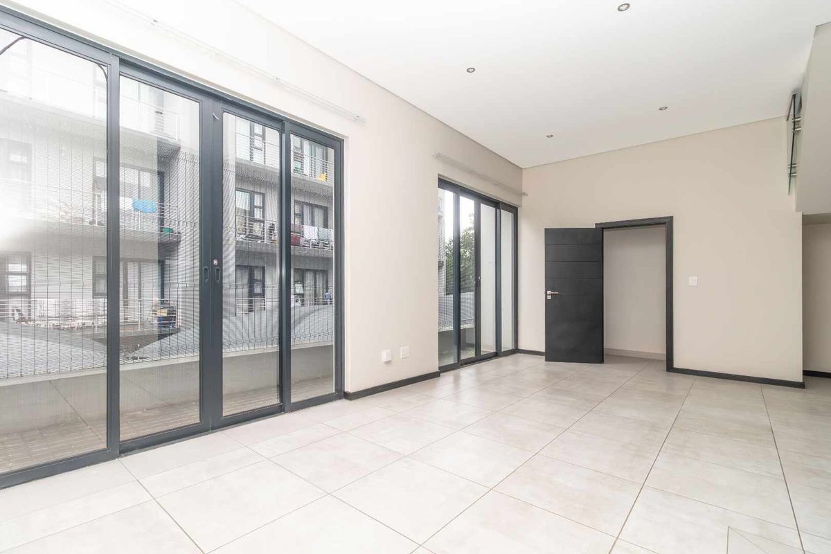 A bright, empty living area featuring large sliding glass doors that provide ample natural light and access to the exterior.