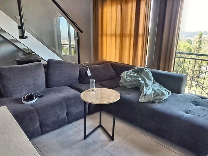 A modern living area featuring tiled floors, a glass-paneled staircase, and direct access to a balcony with scenic views.