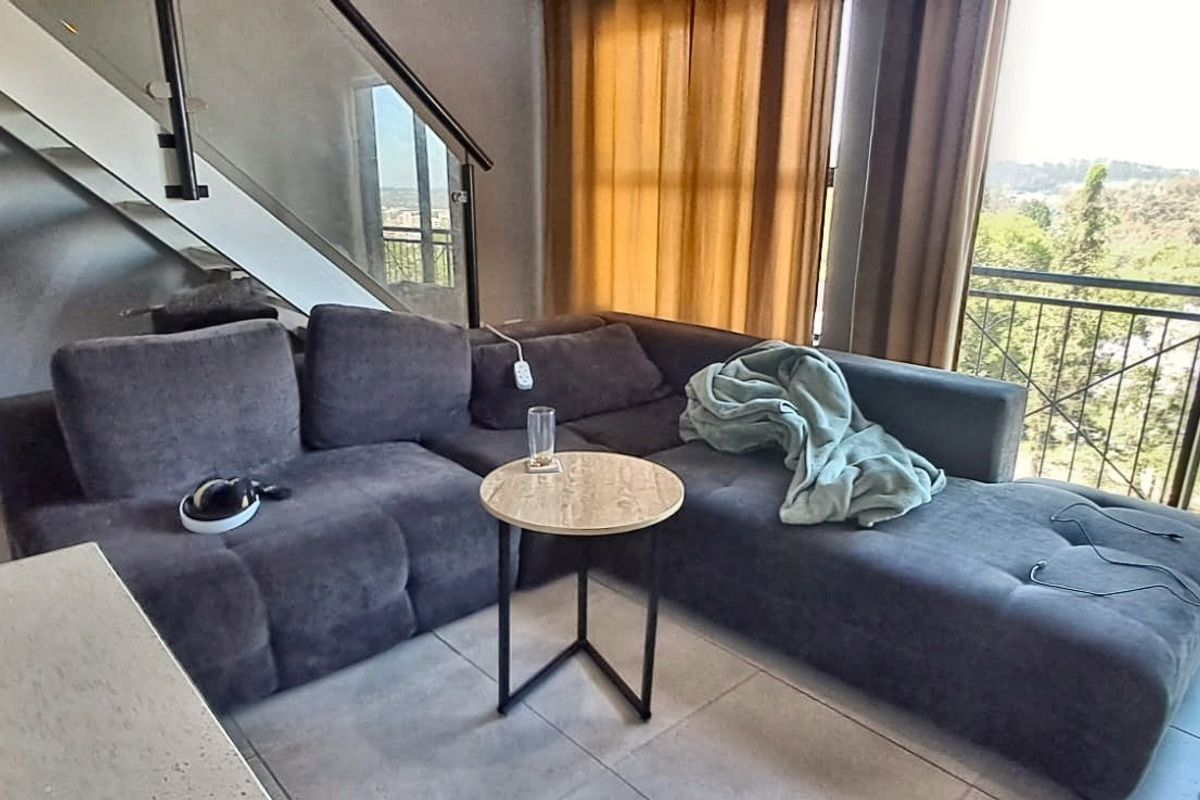 A modern living area featuring tiled floors, a glass-paneled staircase, and direct access to a balcony with scenic views.