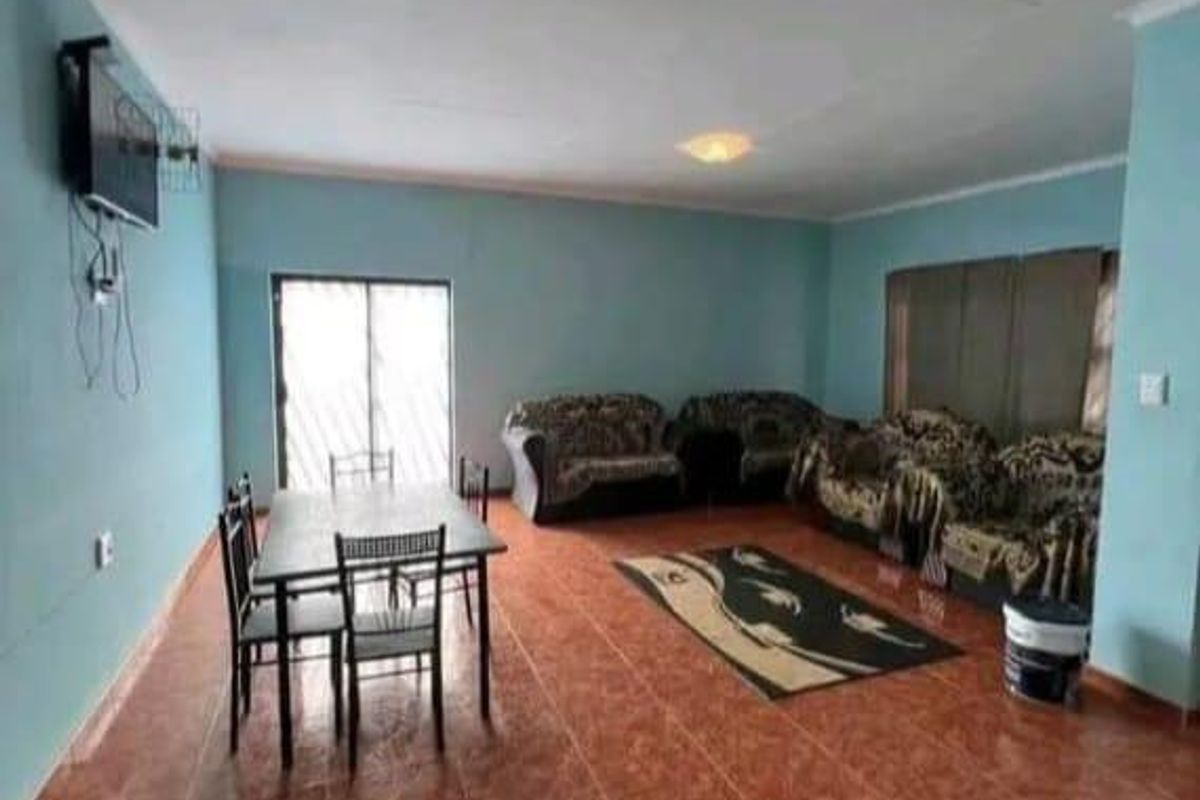 An open-plan living and dining area featuring tiled flooring, ceiling-mounted light fixtures, and sliding door access to the exterior.